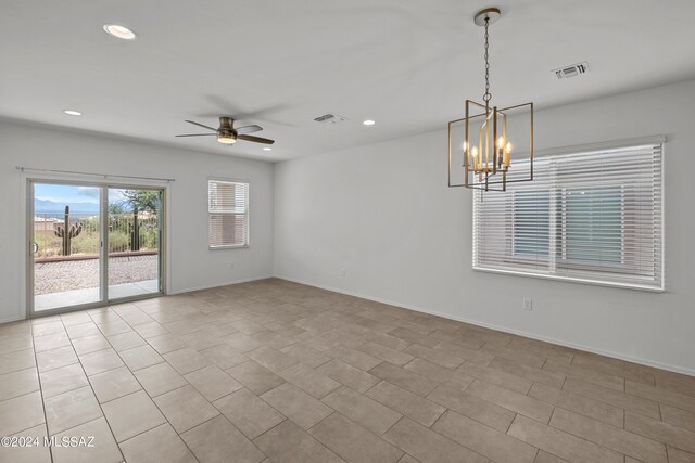 tiled spare room with ceiling fan with notable chandelier