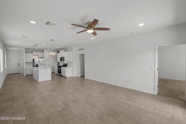 unfurnished living room featuring ceiling fan with notable chandelier and sink