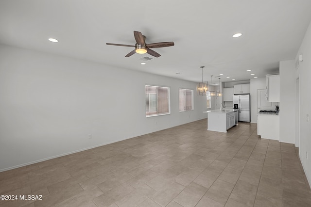 unfurnished living room featuring a sink, ceiling fan with notable chandelier, visible vents, and recessed lighting