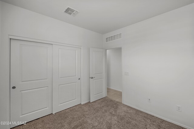 unfurnished bedroom featuring light carpet and a closet