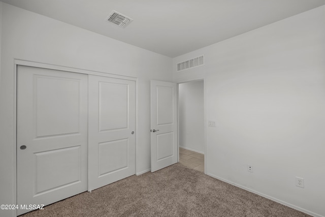 unfurnished bedroom with a closet, carpet flooring, visible vents, and baseboards