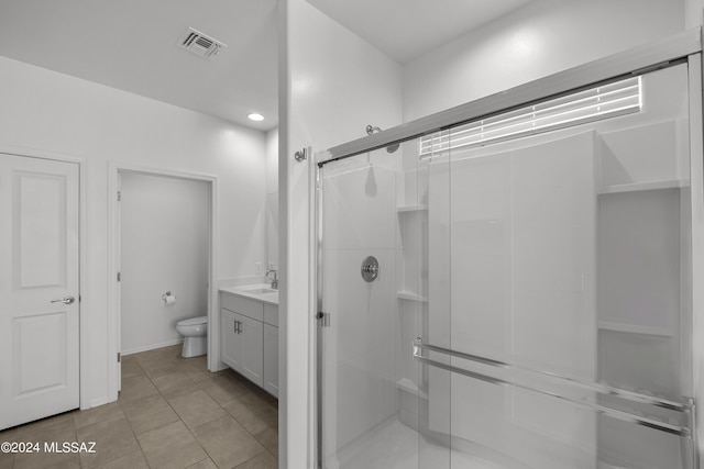 bathroom with toilet, vanity, a shower stall, tile patterned flooring, and visible vents