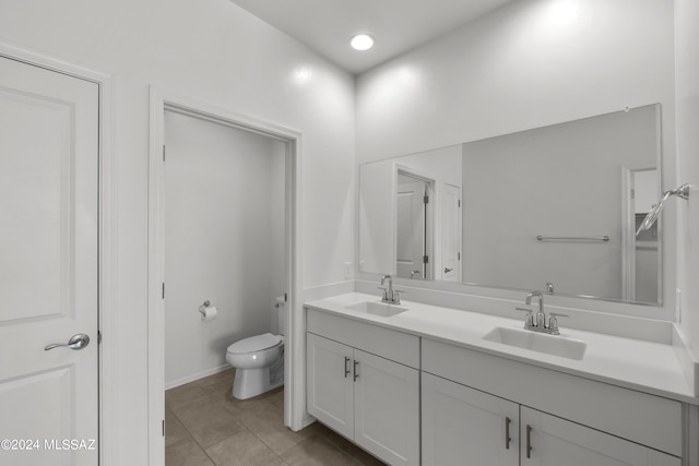full bathroom featuring toilet, a sink, double vanity, and tile patterned flooring