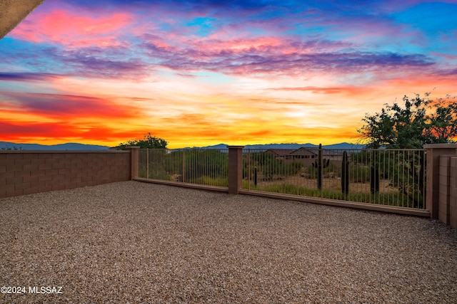 yard at dusk featuring fence and a mountain view