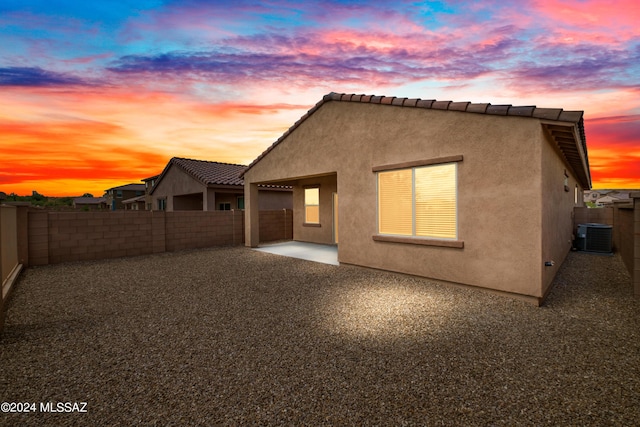rear view of property with a tile roof, a patio area, cooling unit, stucco siding, and a fenced backyard