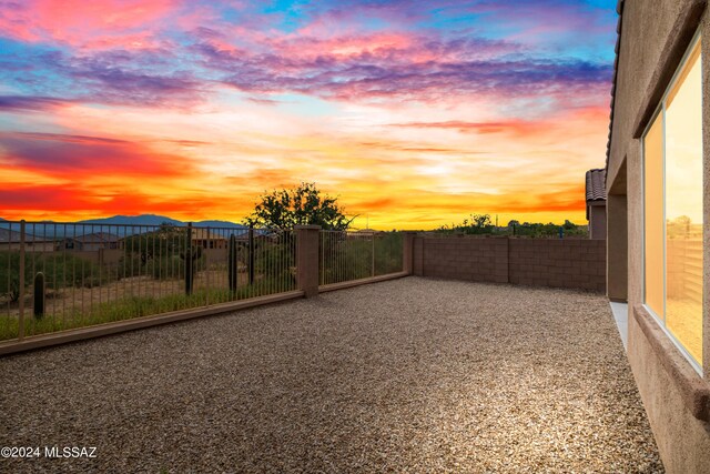 yard at dusk with a patio area, fence, and a mountain view