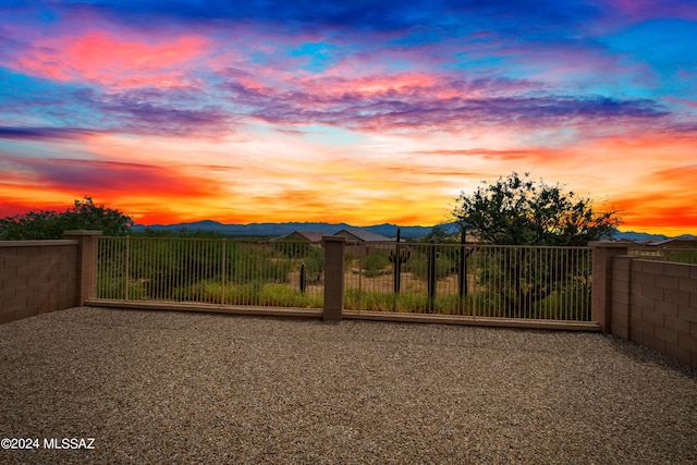 yard at dusk featuring a mountain view and fence