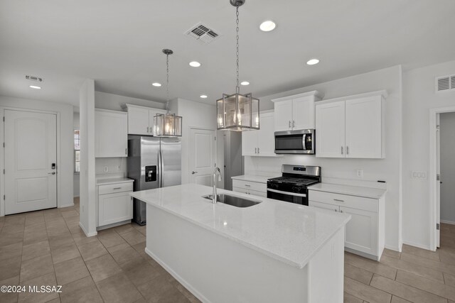 kitchen with stainless steel appliances, white cabinets, a kitchen island with sink, and sink