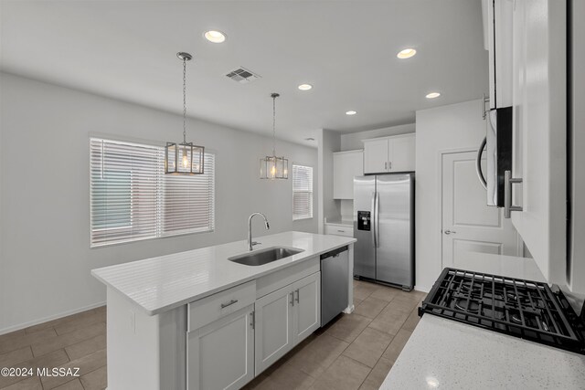 kitchen featuring hanging light fixtures, white cabinets, stainless steel appliances, a kitchen island with sink, and sink