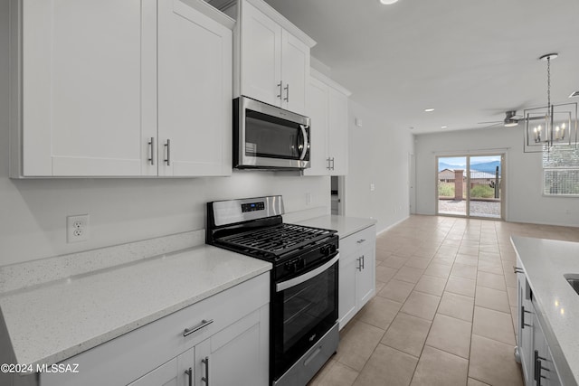 kitchen with white cabinets, ceiling fan, appliances with stainless steel finishes, open floor plan, and light stone countertops