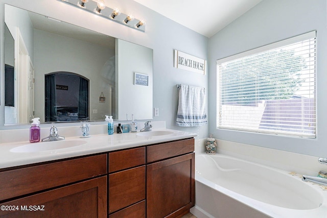 bathroom with lofted ceiling, vanity, and a washtub