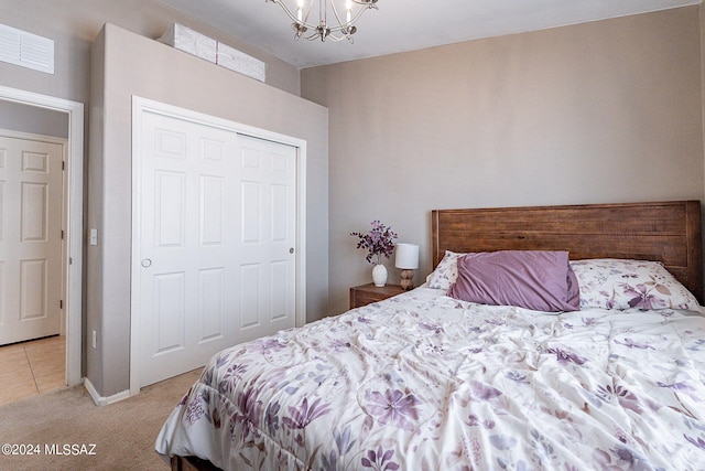 bedroom with a closet, an inviting chandelier, and light carpet