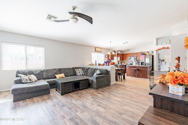 living room featuring light hardwood / wood-style floors, vaulted ceiling, and ceiling fan