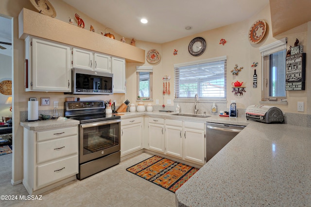 kitchen with light stone countertops, stainless steel appliances, white cabinets, and sink