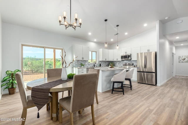 dining room featuring a chandelier, light hardwood / wood-style floors, lofted ceiling, and sink