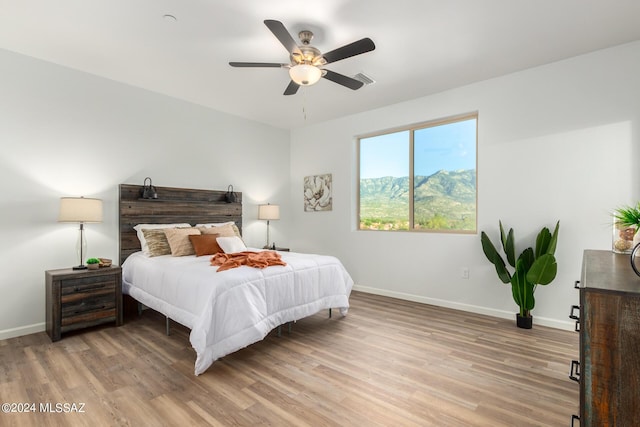 bedroom featuring ceiling fan, a mountain view, and light wood-type flooring