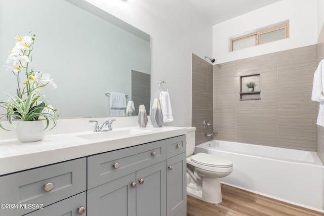 full bathroom featuring vanity, hardwood / wood-style floors, tiled shower / bath, and toilet