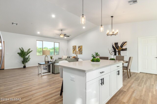 kitchen featuring white cabinetry, hanging light fixtures, lofted ceiling, a kitchen island, and ceiling fan with notable chandelier