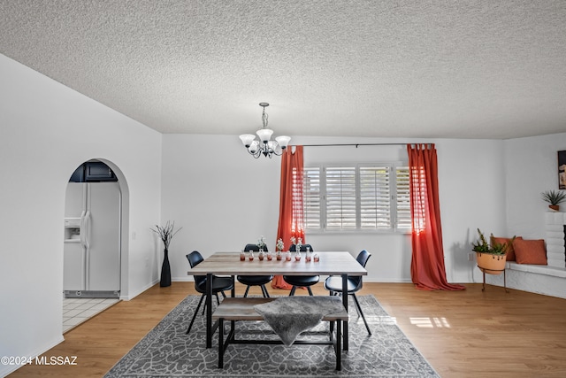 dining space with an inviting chandelier, a textured ceiling, and hardwood / wood-style flooring