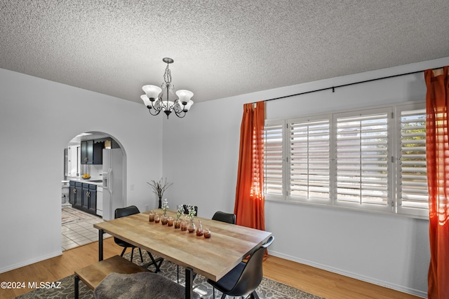 dining room with light hardwood / wood-style floors, a textured ceiling, and a chandelier