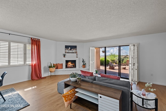 living room featuring a fireplace, a textured ceiling, hardwood / wood-style flooring, and plenty of natural light