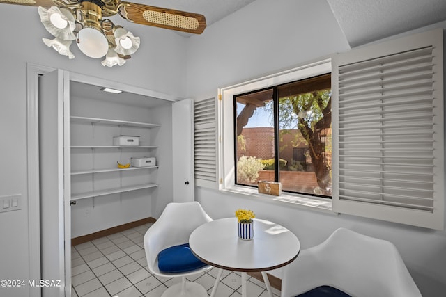 dining area featuring ceiling fan, light tile patterned floors, and a textured ceiling