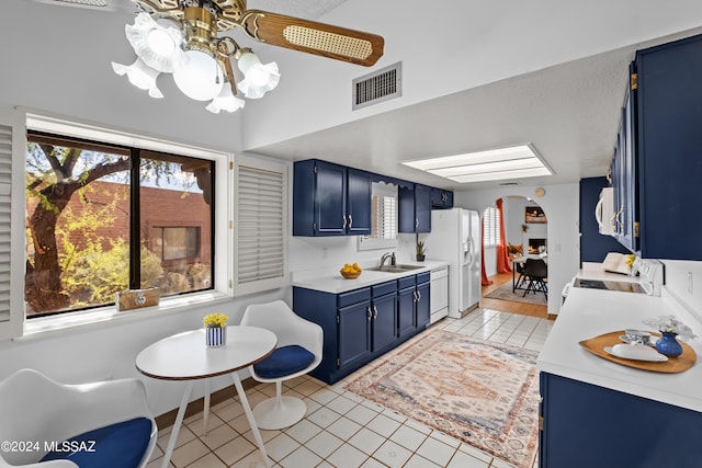 kitchen featuring blue cabinetry, ceiling fan, sink, white appliances, and light tile patterned floors