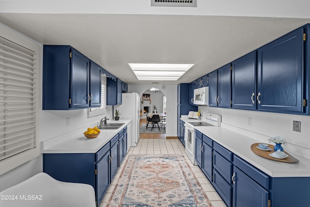 kitchen featuring sink, light tile patterned floors, white appliances, and blue cabinets