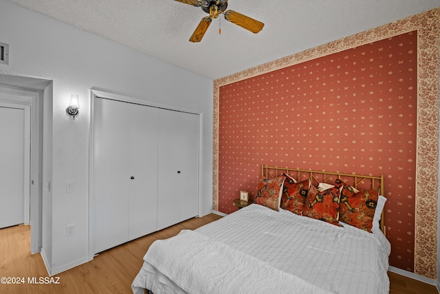 bedroom with a closet, ceiling fan, hardwood / wood-style floors, and a textured ceiling