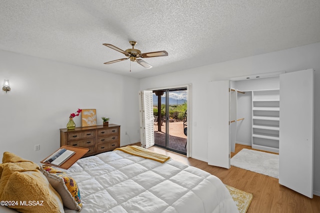 bedroom with access to exterior, ceiling fan, light hardwood / wood-style flooring, a walk in closet, and a closet