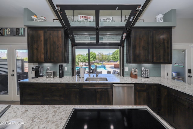 kitchen featuring a wealth of natural light, stainless steel dishwasher, a sink, and dark brown cabinetry