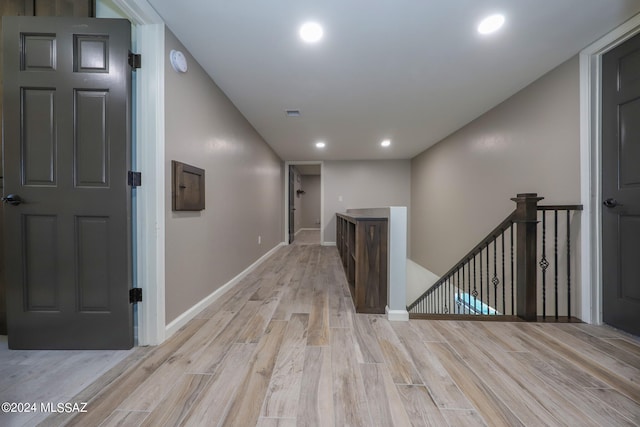 hallway with light wood-style floors, recessed lighting, baseboards, and an upstairs landing