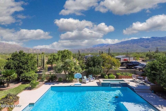 view of swimming pool featuring a pool with connected hot tub, a mountain view, and a patio