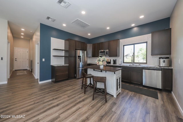 kitchen with appliances with stainless steel finishes, visible vents, a sink, and dark wood-type flooring