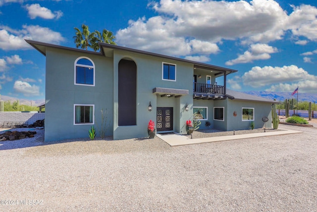 view of front of property featuring french doors, a balcony, and stucco siding