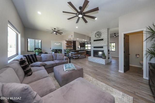 living room featuring a healthy amount of sunlight, a fireplace, visible vents, and wood finished floors