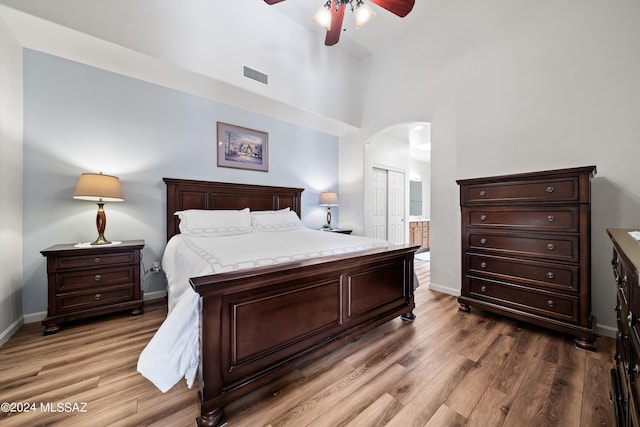bedroom featuring arched walkways, visible vents, a closet, and wood finished floors