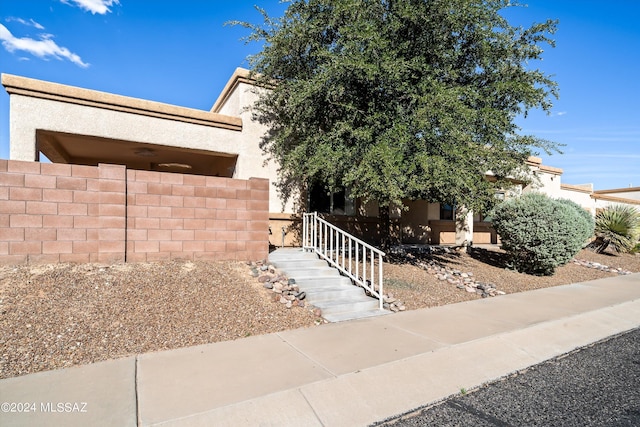 view of front of house featuring stucco siding and fence