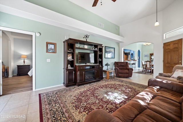 living room with a ceiling fan, light tile patterned flooring, arched walkways, and visible vents