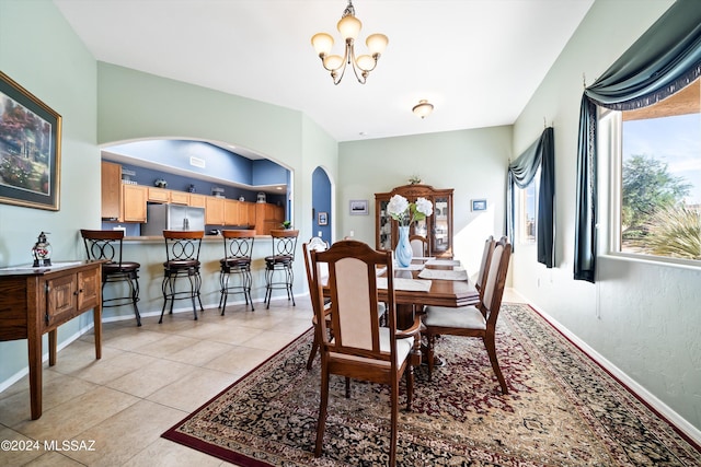 dining area featuring baseboards, a notable chandelier, arched walkways, and light tile patterned floors