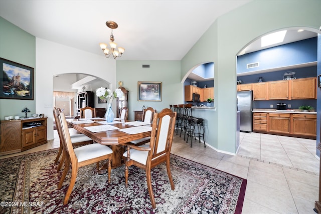dining area with high vaulted ceiling, a chandelier, light tile patterned floors, visible vents, and arched walkways