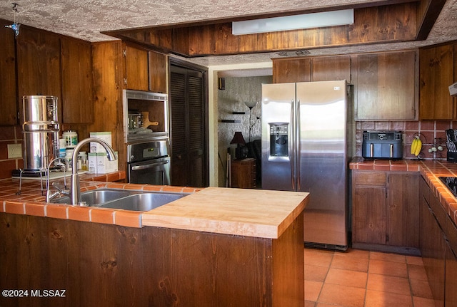 kitchen featuring tile counters, decorative backsplash, sink, and stainless steel appliances