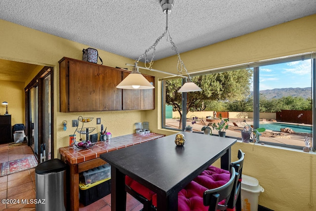 kitchen featuring a textured ceiling, a mountain view, tile patterned floors, and tile countertops