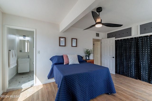 bedroom featuring light hardwood / wood-style flooring, beam ceiling, ceiling fan, and ensuite bathroom