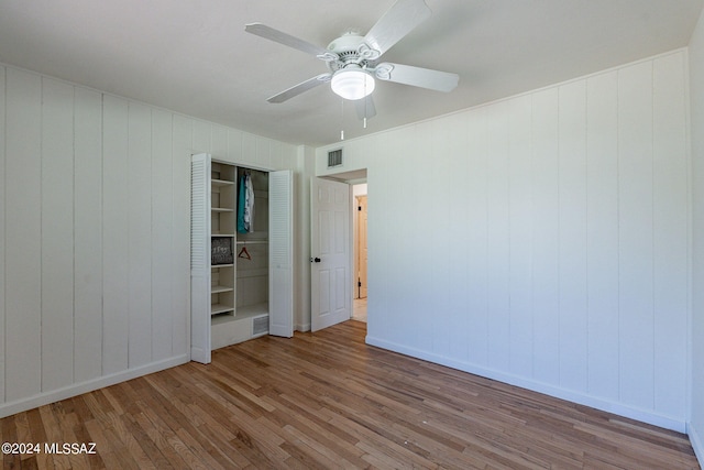 spare room featuring wood-type flooring, wood walls, and ceiling fan