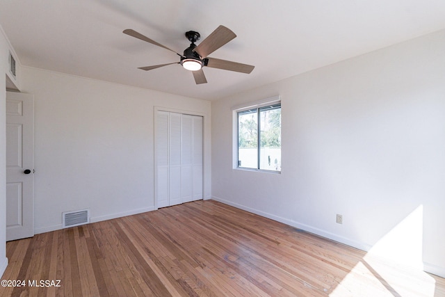 unfurnished bedroom with light wood-type flooring, ceiling fan, and a closet