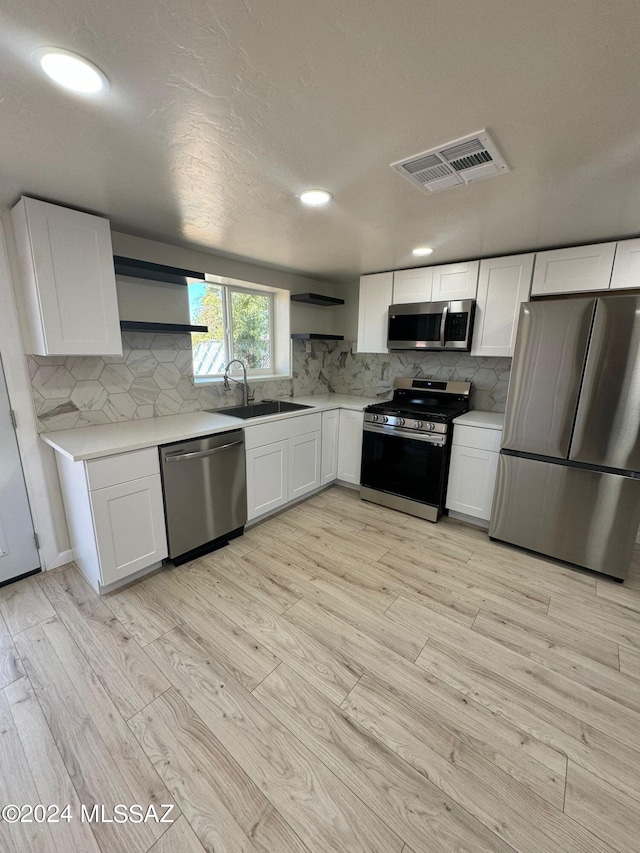 kitchen featuring sink, light hardwood / wood-style flooring, stainless steel appliances, and white cabinets