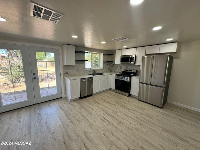 kitchen featuring white cabinets, stainless steel appliances, light wood-type flooring, and sink