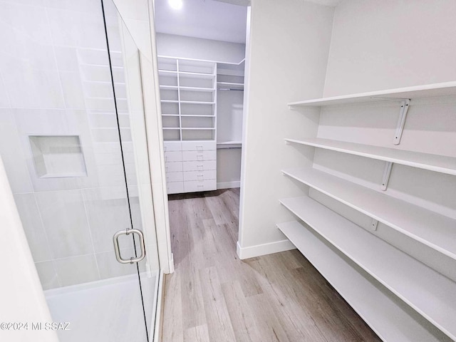 walk in closet with light hardwood / wood-style flooring