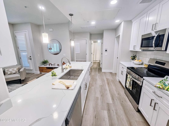 kitchen with pendant lighting, stainless steel appliances, white cabinets, and sink